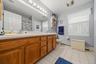 Double vanity with wood-finish cabinetry, dual sinks, and an expansive mirror