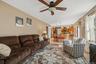 Spacious living area with ceiling fan and wood-finish flooring extending into the kitchen