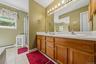 Dual vanity with wood-finish cabinetry, integrated sinks, and a full-width mirror