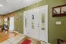 Entryway featuring a white double door with decorative glass inserts, ceramic tile flooring, and wood-finish flooring