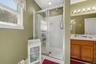 Shower enclosure with sliding glass door, white shower surround, and dual shower heads