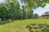 Expansive lawn area with mature trees, a fire pit, and a multi-level wooden deck