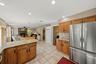 Spacious kitchen featuring warm wood cabinetry, granite countertops, stainless steel appliances including side-by-side refrigerator, and a large cente