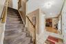 Foyer featuring tile flooring, a staircase with carpet treads and a wood handrail, and recessed lighting