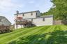 Expansive green lawn with a wood fence, two-story structure with siding, and a large wood deck with stairs