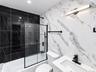 Bathtub with black-framed glass shower enclosure, black tiled shower surround, patterned wall tile, contemporary vanity with integrated sink, and matt