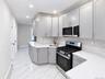 Kitchen featuring light gray cabinetry, white countertops, stainless steel appliances, geometric tile backsplash, and recessed lighting