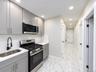 Kitchen featuring stainless steel appliances, grey cabinetry, white countertop, and subway tile backsplash