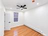 Hardwood flooring, recessed lighting, modern ceiling fan, white paneled door with matte black hardware, and baseboard heating