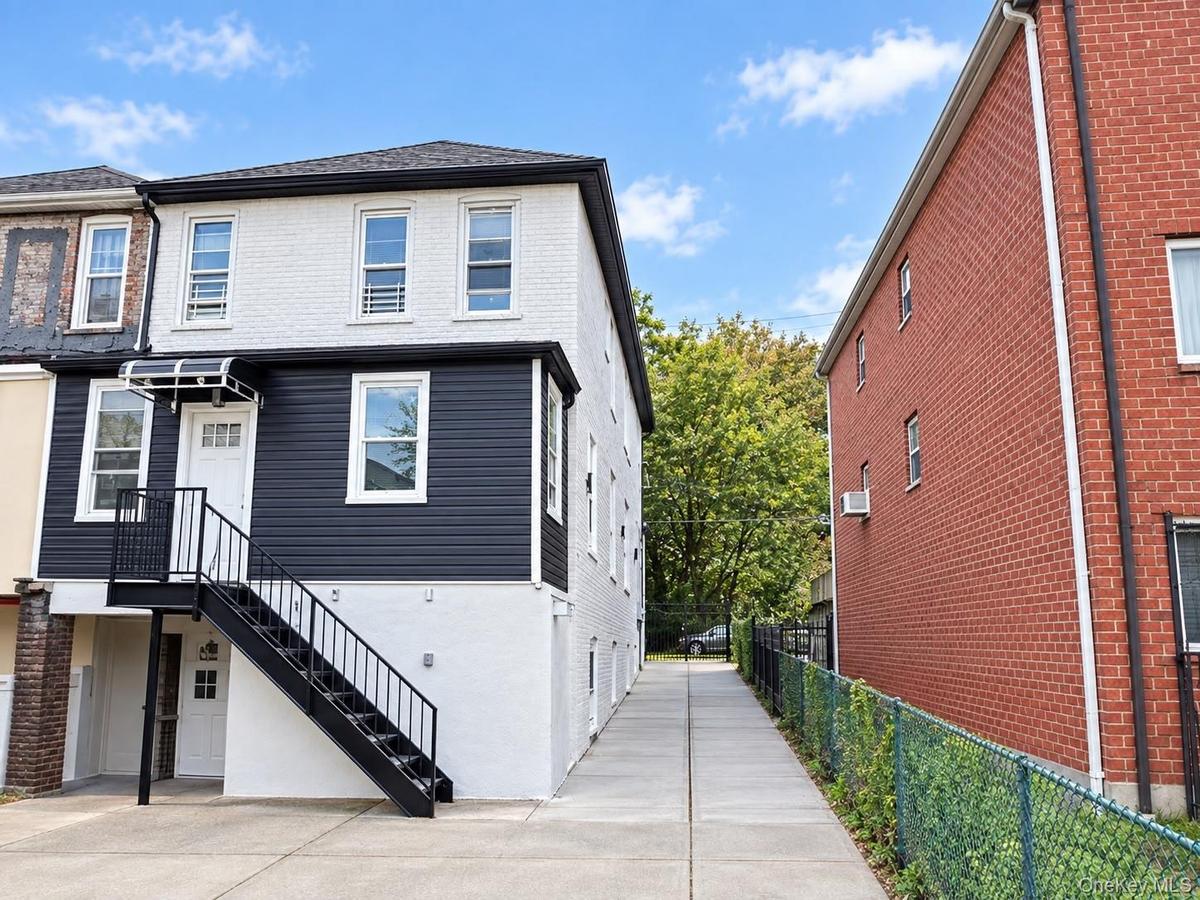 Two-story property featuring white brick and dark siding, black exterior staircase with metal railings, and a covered entry