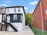 Two-story property featuring white brick and dark siding, black exterior staircase with metal railings, and a covered entry
