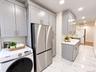 Expansive kitchen featuring light gray cabinetry, stainless steel appliances, white countertops, a tiled backsplash, and large format floor tiles