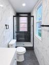 Walk-in shower with dark tile surround, built-in shelving, and black-framed glass enclosure