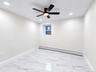 White walls, recessed lighting, ceiling fan with integrated light, marble-look tile flooring, and a baseboard heating unit