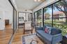 Enclosed Florida room with wood-finish flooring, ceiling fan, and large windows with lush garden views