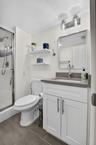 White vanity with shaker-style cabinetry, quartz countertop, and an undermount sink