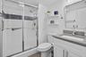 Walk-in shower with sliding glass doors, white tiled walls, and a decorative mosaic accent band