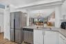 White shaker-style cabinetry, stainless steel appliances, quartz countertops, subway tile backsplash, and wood-finish flooring