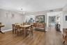 Wood-finish flooring throughout, dining area with a contemporary chandelier, pass-through window to the kitchen