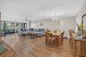 Open-concept living and dining area featuring wood-finish flooring, a contemporary chandelier, and a ceiling fan with integrated lighting