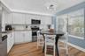 Modern kitchen featuring white shaker cabinetry, stainless steel appliances, wood-finish flooring, and sunlight!