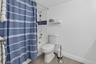 Bathtub with subway tile surround and mosaic accent, white toilet, and tile flooring
