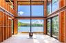 Inside, the main level is defined by a centered wood-burning stove that aligns with the window mullions, creating the illusion of one unbroken wall of