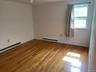 Empty room with a baseboard heating unit, wood finished floors, baseboards, and a ceiling fan