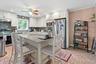 Kitchen featuring appliances with stainless steel finishes, under cabinet range hood, ceiling fan, tasteful backsplash, and a breakfast bar area