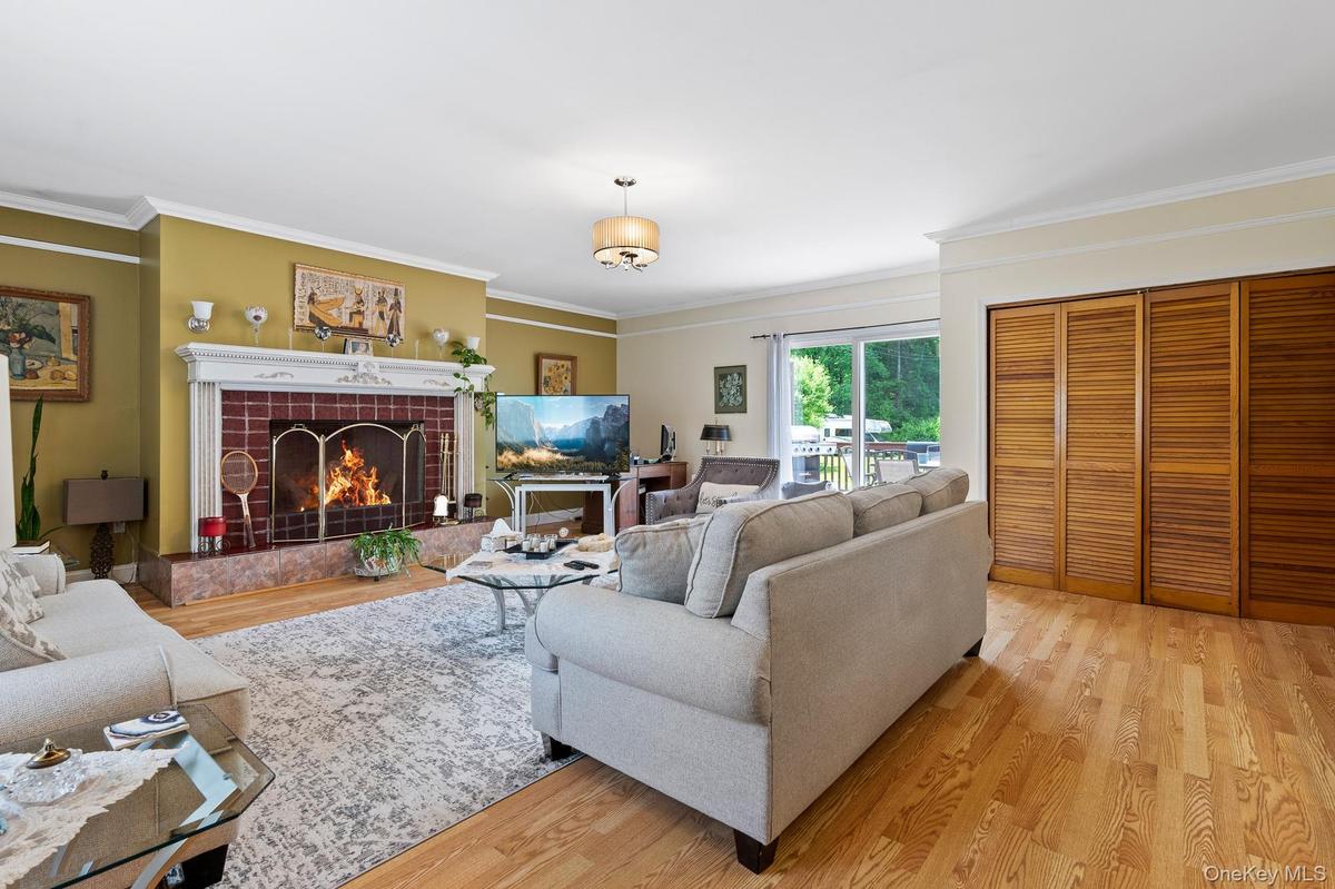 Living area featuring light wood finished floors, crown molding, and a tiled fireplace