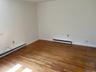 Spare room with baseboard heating, a baseboard heating unit, wood finished floors, baseboards, and ornamental molding
