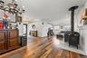 Open living room with hardwood floors, wood-burning stove, built-in bar cabinetry and recessed lighting flowing to the dining area