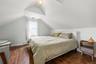 Sloped ceilings with a dormer, wood-finish flooring, and natural light from a single window