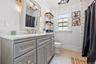 Bathroom featuring a light gray vanity with gold-tone hardware, a white countertop, and a vanity mirror with integrated lighting