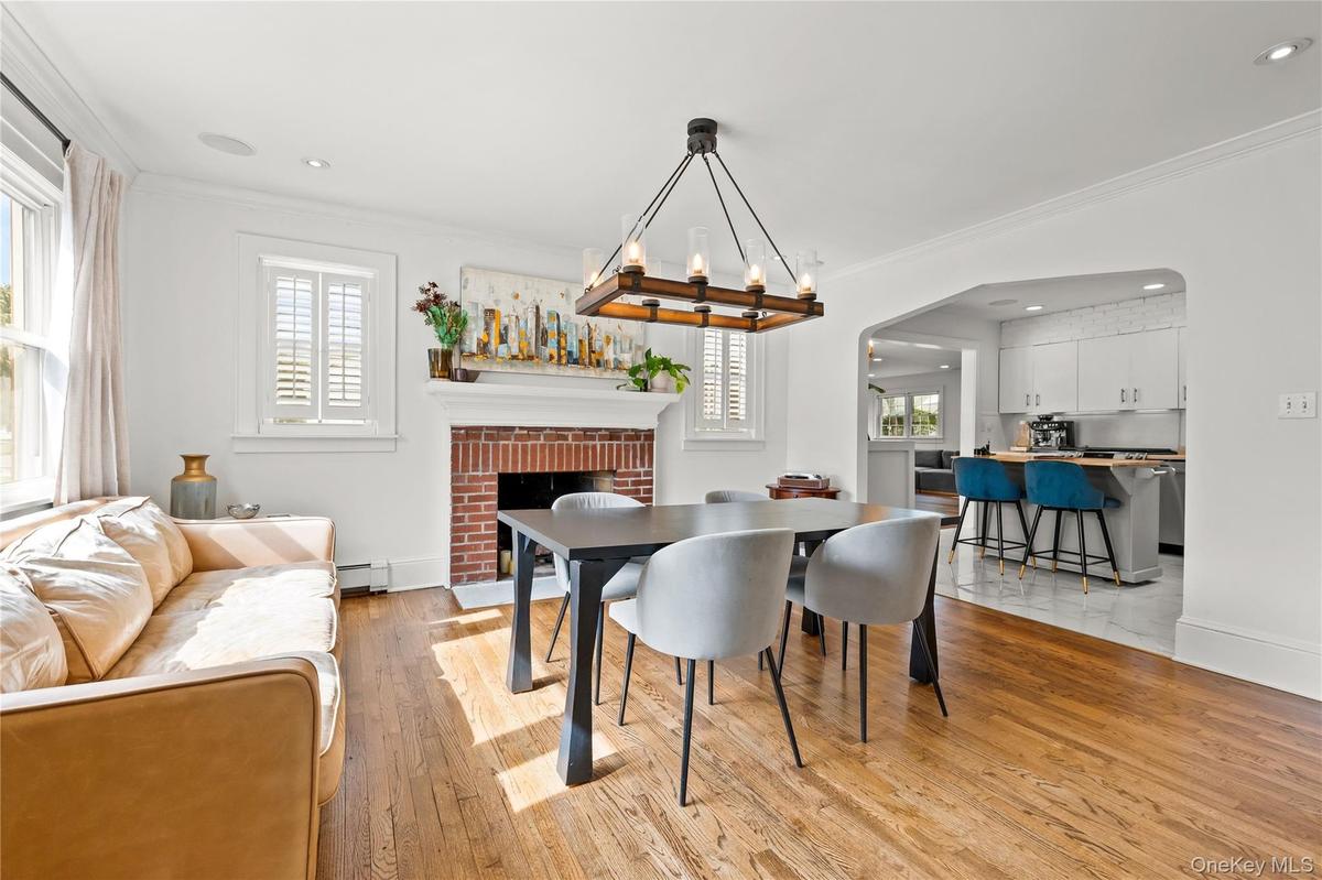 Hardwood flooring, brick fireplace with mantel, recessed lighting, and a kitchen pass-through with built-in cabinetry