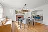 Hardwood flooring, brick fireplace with mantel, recessed lighting, and a kitchen pass-through with built-in cabinetry