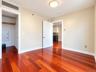 Hardwood-style flooring throughout, featuring a built-in closet with a clothes rod, light-toned walls, and a flush-mount ceiling light