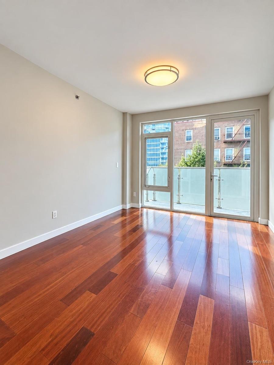 Wood-finish flooring, ceiling-mounted light fixture, light-toned walls, and a glass-paneled door to an outdoor space