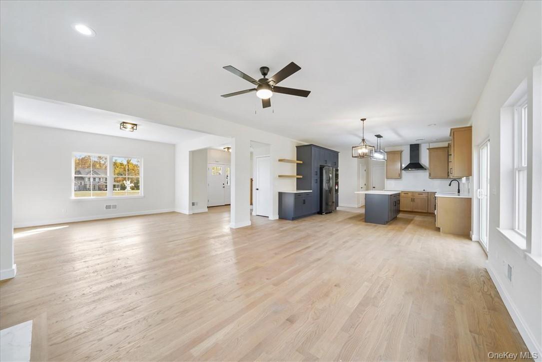 Unfurnished living room with ceiling fan, light hardwood / wood-style flooring, and sink
