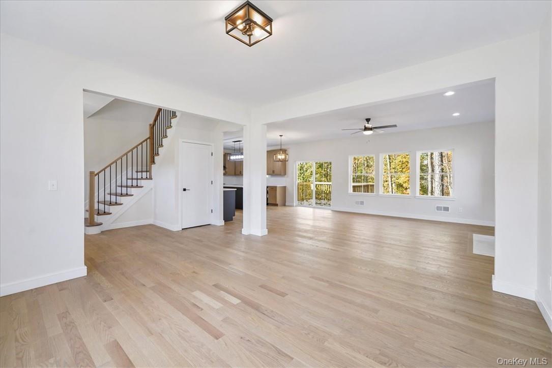 Unfurnished living room with ceiling fan with notable chandelier and light wood-type flooring