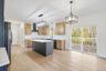 Kitchen featuring appliances with stainless steel finishes, hanging light fixtures, wall chimney range hood, and a kitchen island