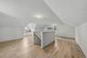 Expansive attic space featuring wood-finish flooring, sloped ceilings, multiple windows, and track lighting