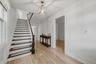 Wood-finish flooring, staircase with dark wood-finish treads and white risers, square caged light fixture, and white wall finishes