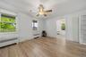 Wood-finish flooring, two windows with blinds, ceiling fan, and built-in shelving