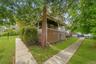 Siding exterior with a covered porch, mature trees, concrete walkways, and a ramp access point