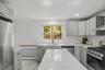 Modern kitchen with light grey cabinetry, white subway tile backsplash, stainless steel appliances, and a central island with a white countertop