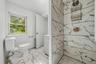 Bathroom featuring a tiled shower with a rain shower head, hexagonal floor tiles, and a window