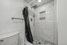 Shower featuring white marble-look subway tile, mosaic tile shower floor, built-in shower niche, and a rain shower head with an additional handheld sh