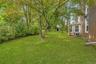 Expansive lawn area with mature trees and established perimeter shrubbery