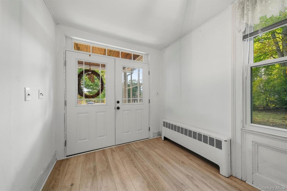 Wood-finish flooring, white walls, and a front entry with glass paneled doors